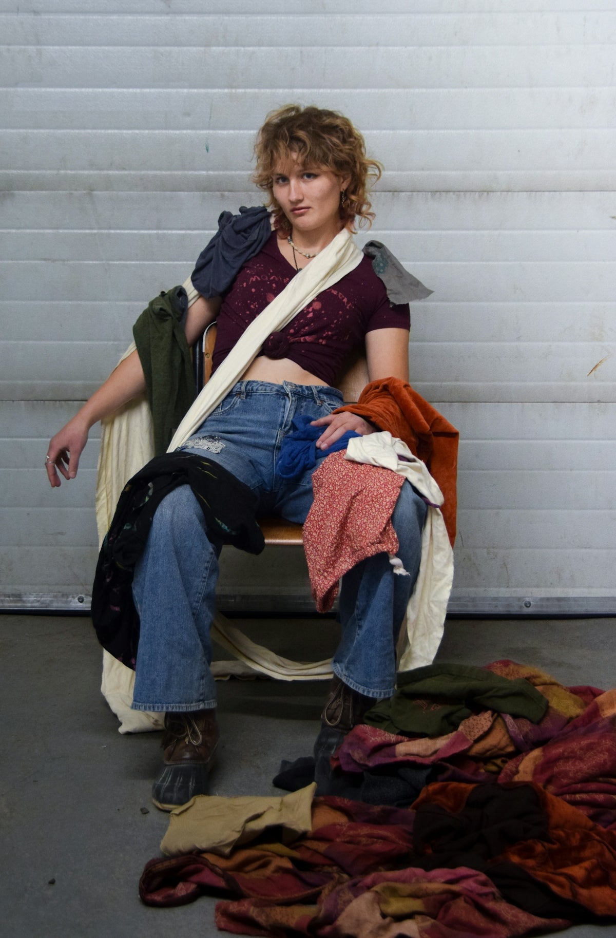 Woman draped in colorful fabrics sits on chair